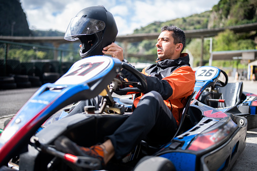 Portrait of professional karting racer on the track .