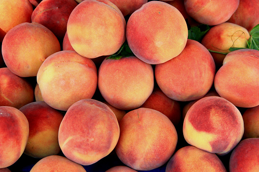 Photo of large juicy ripe sweet orange-pink peaches at the market
