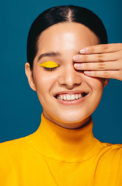 istock Wearing vibrant eye shadow, woman covers her eye in a studio 1483306617