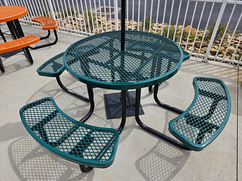 Green round metal outdoor dining table with attached bench seats