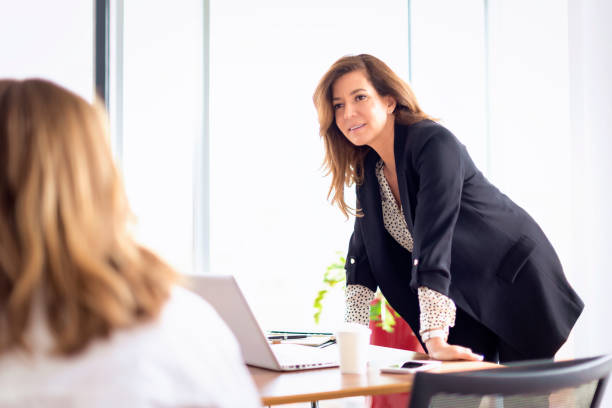 istock Executive business woman standing at desk and using laptop while discussing with an unrecognizable professional female 1483311172