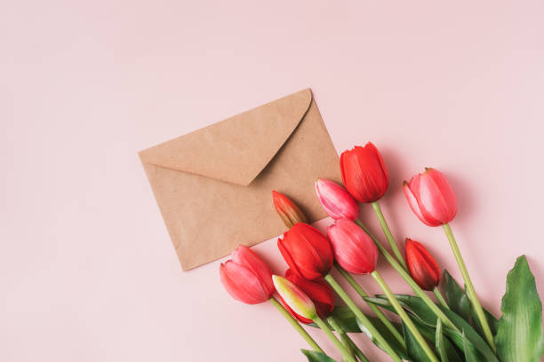 istock Red blooming tulips with craft envelope on pink background 1483312644