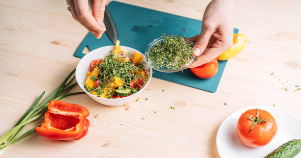 istock Lady sprinkles vegetable salad with microgreens 1483313643