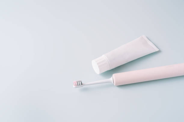 istock Pink electric toothbrush with toothpaste on a blue background 1483313689