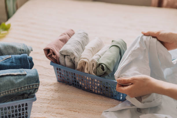 istock Lady folds her clothes into containers while sitting on the bed 1483315278
