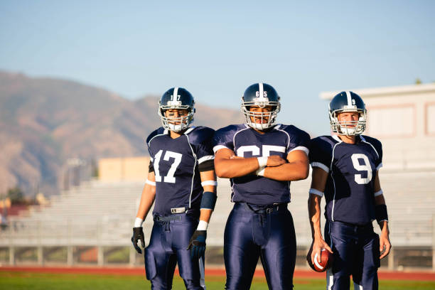 American Football Team Three American Football players in full tackle football pads stand as a team ready to play. Image taken in Utah, USA. football helmet and ball stock pictures, royalty-free photos & images