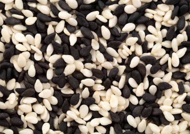 pile de graines de sésame en noir et blanc en arrière-plan, vue de dessus. - white sesame seed photos et images de collection