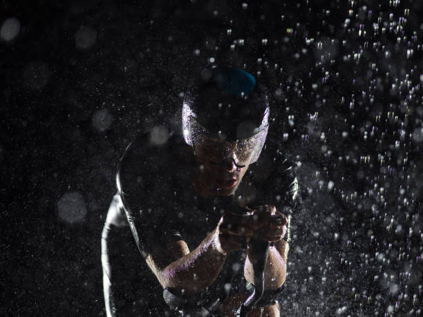 istock A triathlete braving the rain as he cycles through the night, preparing himself for the upcoming marathon. The blurred raindrops in the foreground and the dark, moody atmosphere in the background add to the sense of determination and grit shown by the at 1483319717