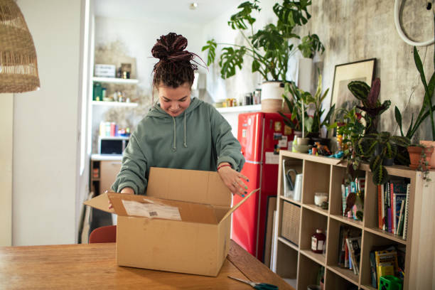 istock Young woman opening up a box she received in the mail 1483320962
