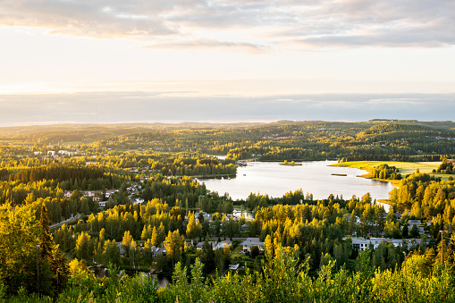 Forest and lake in Finland. Finnish nature in summer. Beautiful landscape and aerial view to town at sunset. Nordic country outdoor scenery. Countryside in Scandinavia. Green trees and water at dawn.
