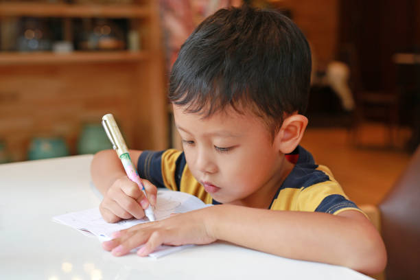 Portrait of adorable cute charming boy schoolchild lying doing hometask living room apartment indoors remote education.