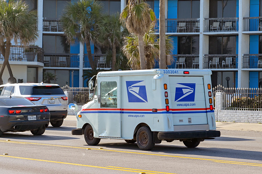 Galveston, Texas, USA - February 2023: Small truck used by the United States Postal Service driving on one of the city's streets.