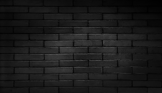 black brick wall, dark background for design. black painted modern brick wall used as panoramic background in close up view. detail of a dark black brick wall texture.