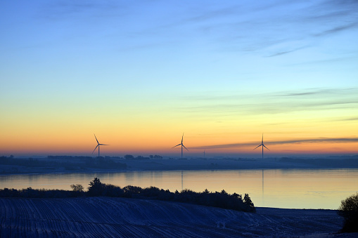 Sunset behind power generating windturbines on a partly cloudy evening in Denmark