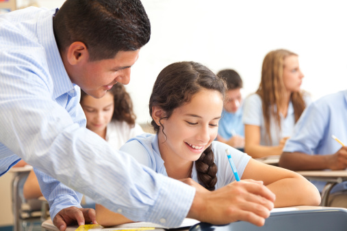 High school girl in class receiving help from her teacher. 