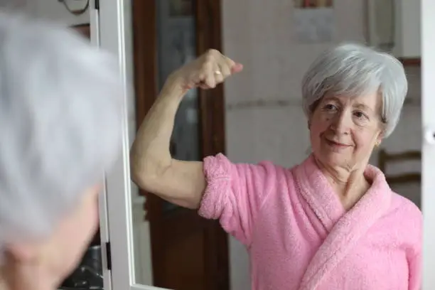 Photo of Senior woman flexing biceps in the mirror