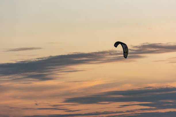 Gothenburg, Sweden - October 10 2021: Kiteboarders kitesurfing in the sunset by a beach .