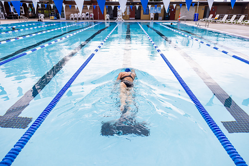 High quality stock photos of a middle-aged master's class swimmer practicing in an outdoor public pool early in the morning.