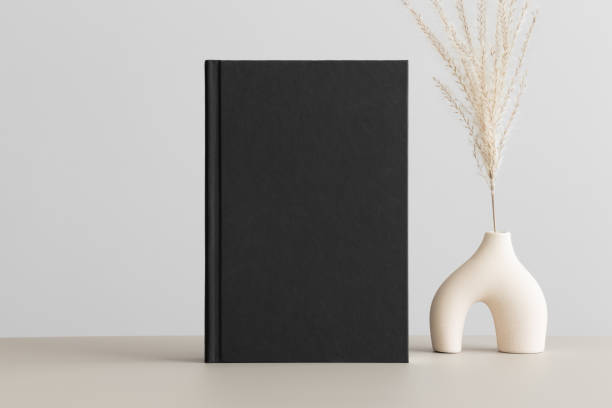 istock Black book mockup with a reed pampas decoration on the beige table. 1483337132