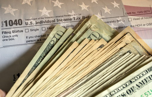 IRS form 1040-SR and dollars still life background merged with 'Stars and stripes'.