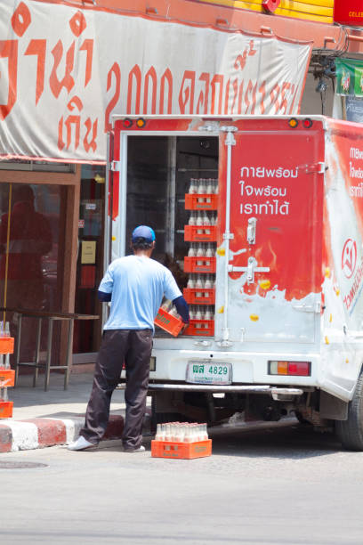 Thai man is delivering soy milk boxes to a shop in street Chokchai 4 in Bangkok Ladprao. Truck has branding of company and soy milk advertising,