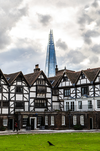 Tower of London Queens Quarters with The Shard in Background in London England United Kingdom During Daytime with Crow on Ground and Clouds in Sky. New and Old Contrast.