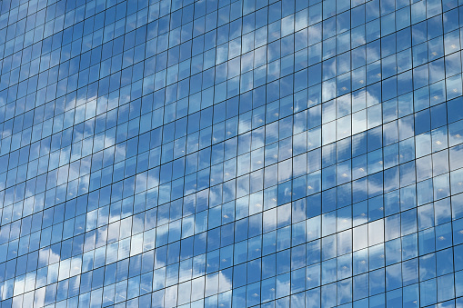 low angle view of a contemporary glass skyscraper reflecting the blue sky