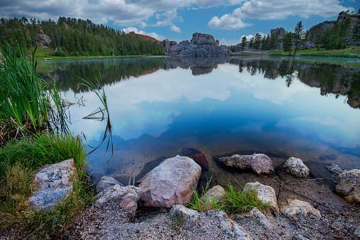 Beautiful body of water with reflection. Cloudscape over lake rocks. South Dakota USA tourism