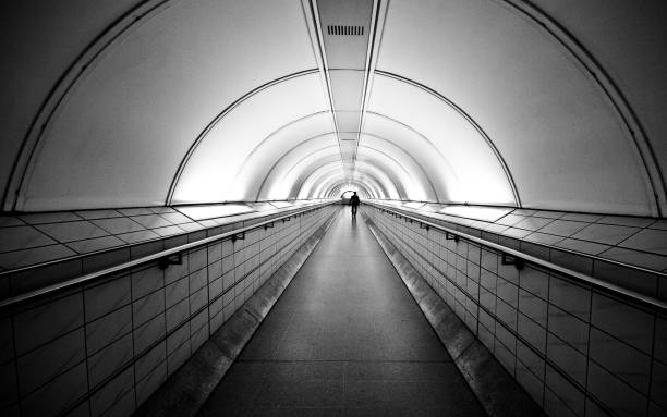 istock Grayscale of an underground train station interior, with a man walking on an empty platform 1483355812