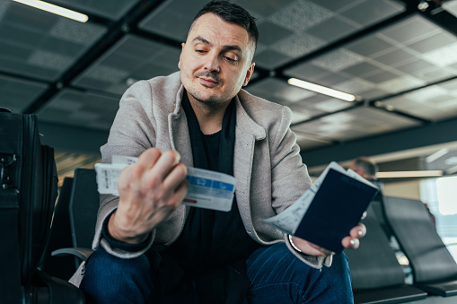Man looking at his passport and boarding card, while awaiting flight at the airport