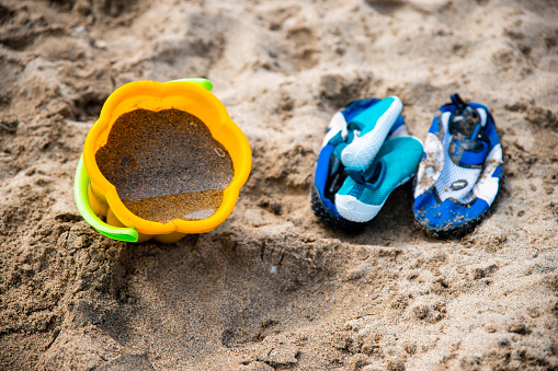 Beach toys and sea shoes on sand. Copy space