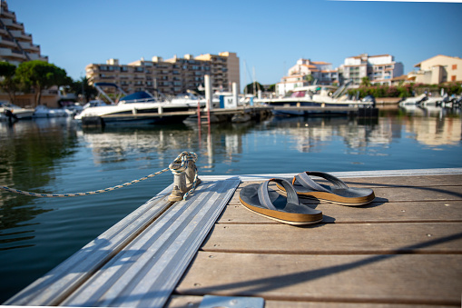 Male flip flops on a Boat pier in sea marina with city in background