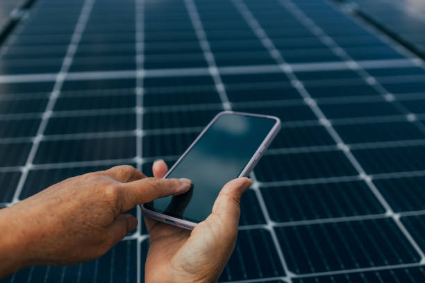 istock Close-up of young engineer hand holding smartphone on panel background on sunny day, green alternative energy concept. high quality photo 1483360038