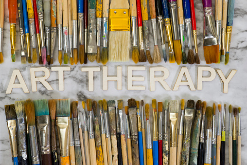 Artist paintbrushes in a jar over colorful background