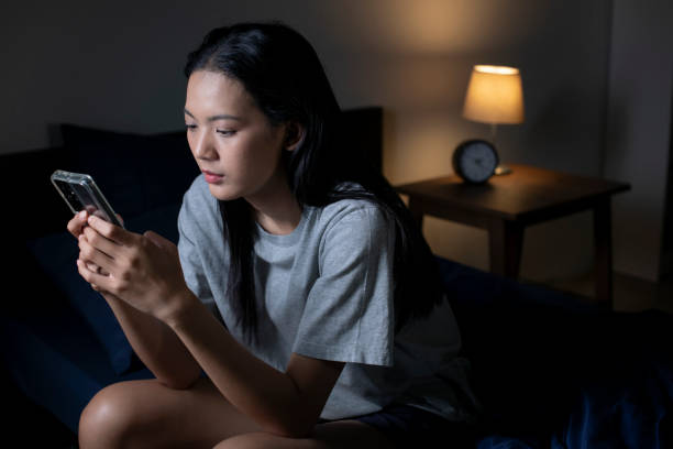 istock Exhausted young Asian woman using smartphone late at night. 1483361648