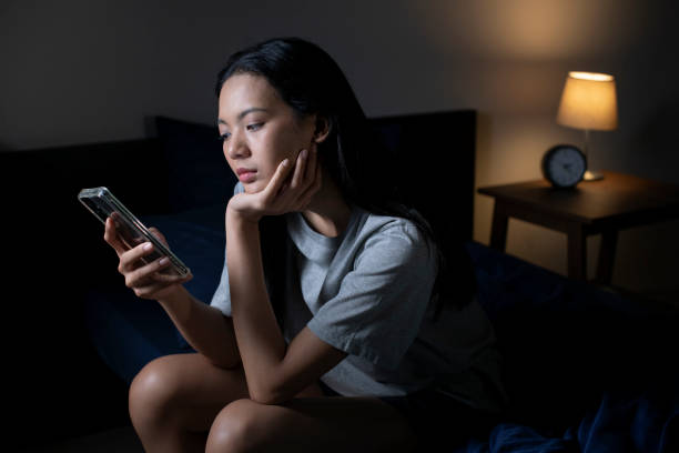 istock Exhausted young Asian woman using smartphone late at night. 1483361651