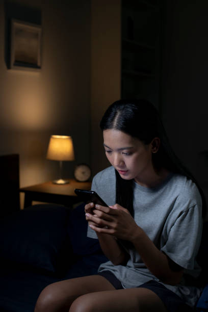 istock Exhausted young Asian woman using smartphone late at night. 1483361668