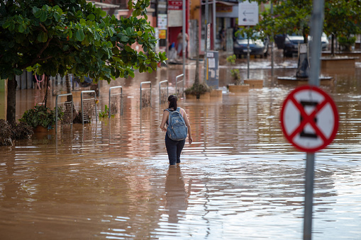 woman walking through flooded streets of the city of franco da rocha