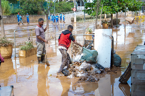 people working on cleaning the flooded streets of the city of franco da Rocha