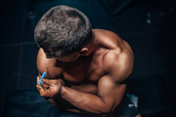 Man injecting steroids Male body builder injecting himself with steroids in the shoulder. man muscular chest stock pictures, royalty-free photos & images
