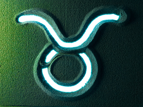 Hand drawing the taurus horoscope sign symbol in the Green Sand. Male hand writes the Aries horoscope sign symbol on the green sand with white backlight. Top view 4k resolution