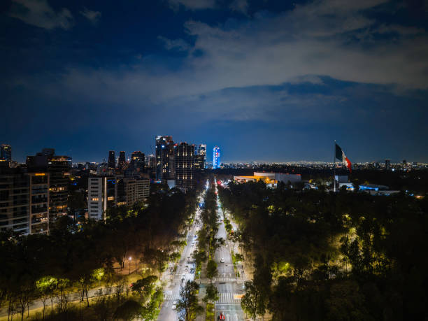 Reforma Avenue at Mexico City, passing through Chapultepec Park with skyscrapers in the background at sunset