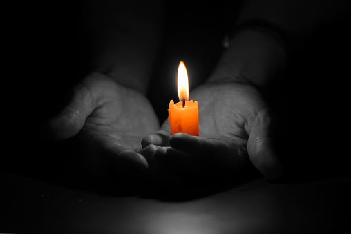 a single candle lit at night and in the background are light reflections