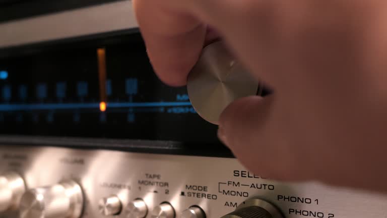 close-up of a hand using the seek button of an old radio