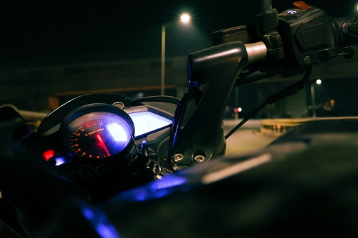 An image of a motorcycle dashboard featuring illuminated instrumentation and controls