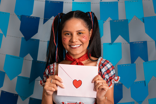 Brazilian Festa Junina, happy woman showing love letter at Party in June in caipira clothes
