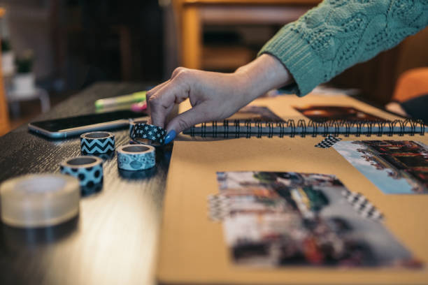 istock Close-up image of an unrecognizable middle-aged woman's hands selecting and picking up a roll of washi tape to use in her handmade kraft travel album. 1483376850