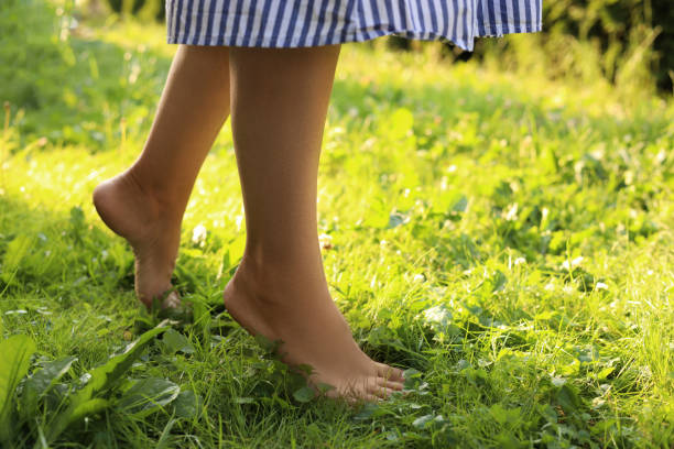 istock Woman walking barefoot on green grass, closeup. Space for text 1483377304