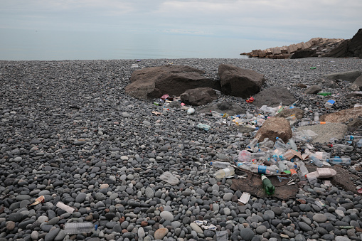 Garbage scattered on pebbles near sea. Recycling problem