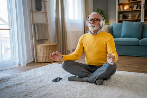 Mature senior man practice guided meditation manifestation at home stock photo